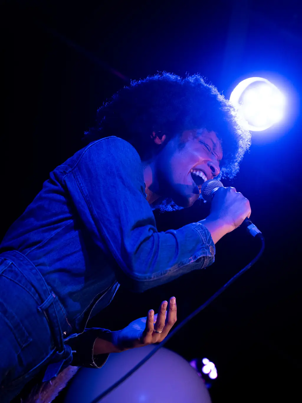 Zangeres zingt vol overgave onder blauw podiumlicht